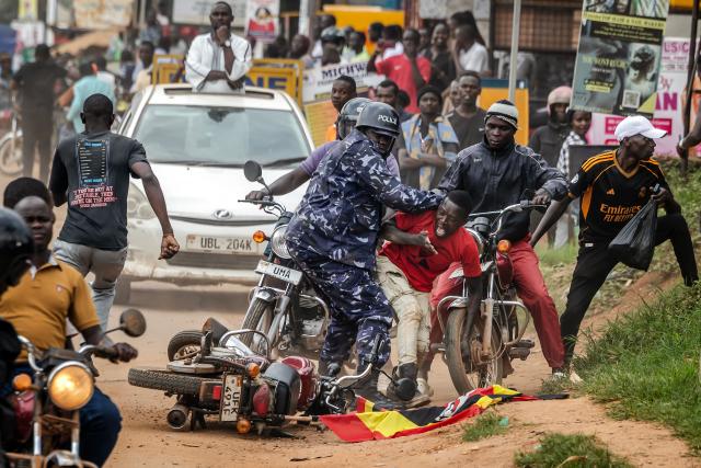 A Ugandan police officer pushes a supporter of opposition leader and presidential candidate for the National Unity Platform (NUP) Robert Kyagulanyi Ssentamu, popularly known as Bobi Wine, as police try to control crowds during a campaign rally in Mukono on January 9, 2026, ahead of the 2026 Ugandan general elections. (Photo by Luis TATO / AFP)