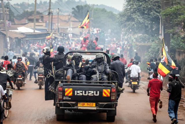 Ugandan police officers ride in a pickup truck amid clouds of tear gas as they follow supporters of opposition leader and presidential candidate for the National Unity Platform (NUP) Robert Kyagulanyi Ssentamu, popularly known as Bobi Wine, during a campaign rally in Mukono on January 9, 2026, ahead of the 2026 Ugandan general elections. (Photo by Luis TATO / AFP)
