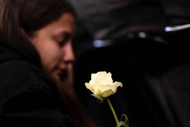 An attendees holds a white rose during a tribute ceremony for the victims of the deadly fire that ripped through the bar Le Constellation in Crans-Montana on New Year's Eve, in Martigny, on January 9, 2026. All of Switzerland will mark a national day of mourning on January 9 for the dozens of mostly teenagers killed when fire ravaged a ski resort bar crammed with New Year revellers. Just over a week after the tragedy at the Le Constellation bar in Crans-Montana, which left 40 dead and 116 injured, the wealthy Alpine nation will come to a standstill for a minute of silence at 2:00 pm (1300 GMT). (Photo by MICHAEL BUHOLZER / POOL / AFP)