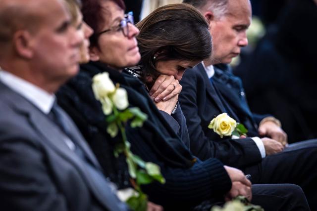 Participants hold flowers during a tribute ceremony for the victims of the deadly fire that ripped through the bar Le Constellation in Crans-Montana on New Year's Eve, in Martigny, on January 9, 2026. All of Switzerland will mark a national day of mourning on January 9 for the dozens of mostly teenagers killed when fire ravaged a ski resort bar crammed with New Year revellers. Just over a week after the tragedy at the Le Constellation bar in Crans-Montana, which left 40 dead and 116 injured, the wealthy Alpine nation will come to a standstill for a minute of silence at 2:00 pm (1300 GMT). (Photo by MICHAEL BUHOLZER / POOL / AFP)