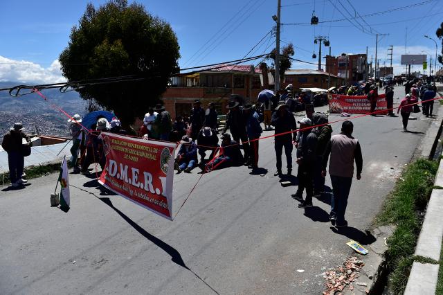 Members of Bolivia's teachers unions block the road linking El Alto-La Paz in protest against the elimination of hydrocarbon subsidies in Bolivia -now entering their third week- in El Alto, on January 9, 2026. Protests against centre-right President Rodrigo Paz’s economic measures, ending fuel subsidies and doubling petrol and diesel prices, have led to 32 roadblocks, several on major routes, according to the state-owned Bolivian Road Administration (ABC). (Photo by Jorge BERNAL / AFP)