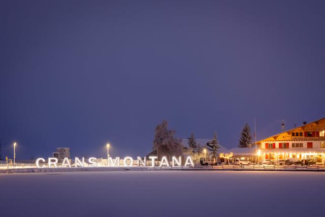 Attendees gather in mourning, placing messages, candles, and flowers at a memorial site in front of the bar “Le Constellation” during a national day of mourning in Crans-Montana, on January 9, 2026, in tribute to the victims of the fire that ravaged the bar on New Year’s Eve, killing 40 people and injuring 116 others, most of them teenagers. All of Switzerland will mark a national day of mourning on January 9 for the dozens of mostly teenagers killed when fire ravaged a ski resort bar crammed with New Year revellers. Just over a week after the tragedy at the Le Constellation bar in Crans-Montana, which left 40 dead and 116 injured, the wealthy Alpine nation will come to a standstill for a minute of silence at 2:00 pm (1300 GMT). (Photo by MAXIME SCHMID / AFP)