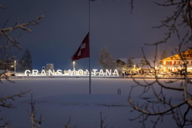 Attendees gather in mourning, placing messages, candles, and flowers at a memorial site in front of the bar “Le Constellation” during a national day of mourning in Crans-Montana, on January 9, 2026, in tribute to the victims of the fire that ravaged the bar on New Year’s Eve, killing 40 people and injuring 116 others, most of them teenagers. All of Switzerland will mark a national day of mourning on January 9 for the dozens of mostly teenagers killed when fire ravaged a ski resort bar crammed with New Year revellers. Just over a week after the tragedy at the Le Constellation bar in Crans-Montana, which left 40 dead and 116 injured, the wealthy Alpine nation will come to a standstill for a minute of silence at 2:00 pm (1300 GMT). (Photo by MAXIME SCHMID / AFP)