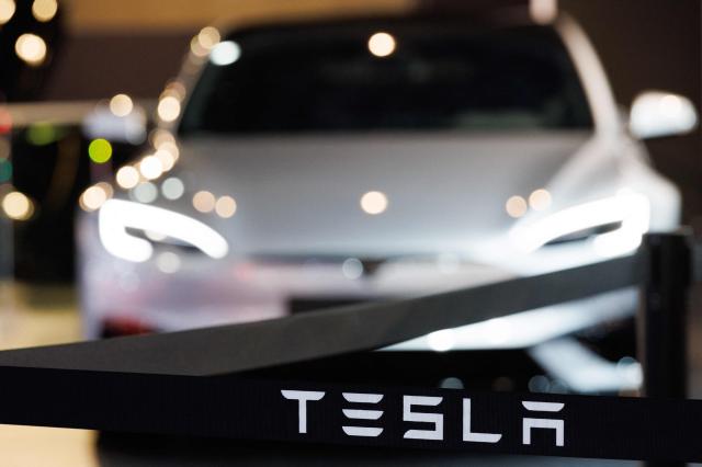 This photograph shows the logo of US automobile manufacturer Tesla next to a Tesla car during a press opening of the 102th edition of the Brussels Motor Show, at Brussels Expo in Brussels on January 9, 2026. (Photo by BENOIT DOPPAGNE / Belga / AFP) / Belgium OUT