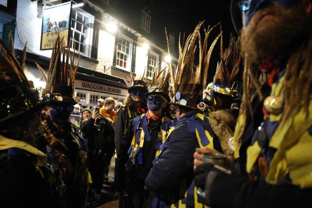 The Hook Eagle Morris Men gather outside the Waggon and Horses public house ahead of a performance during the annual Wassail night in Hartley Wintney, west of London on January 9, 2026. The event, held near to Twelfth Night, celebrates both the passing of Christmas and the future good health of the fruit trees. Traditionally the custom involved the local farm workers visiting the orchard after dark with shotguns, horns, food and a large pail of cider. They would make a loud noise to raise the Sleeping Tree Spirit and to scare off demons. Cider would be poured over the roots and pieces of toast placed in the branches as a gift to the spirit of the tree. The wassail song is sung as a blessing or charm to bring fruitfulness or even in admonishment not to fail in the upcoming year. (Photo by Adrian DENNIS / AFP)