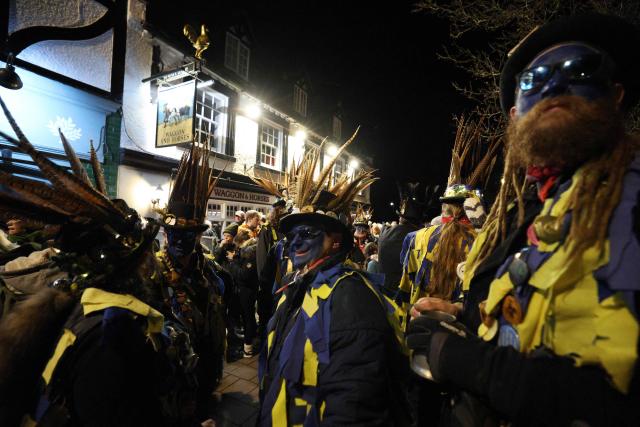 The Hook Eagle Morris Men gather outside the Waggon and Horses public house ahead of a performance during the annual Wassail night in Hartley Wintney, west of London on January 9, 2026. The event, held near to Twelfth Night, celebrates both the passing of Christmas and the future good health of the fruit trees. Traditionally the custom involved the local farm workers visiting the orchard after dark with shotguns, horns, food and a large pail of cider. They would make a loud noise to raise the Sleeping Tree Spirit and to scare off demons. Cider would be poured over the roots and pieces of toast placed in the branches as a gift to the spirit of the tree. The wassail song is sung as a blessing or charm to bring fruitfulness or even in admonishment not to fail in the upcoming year. (Photo by Adrian DENNIS / AFP)
