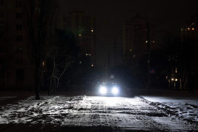 A car with headlights drives on a non-illuminated road during a power outage in Kyiv on January 9, 2026, following Russian missile and drone attacks on Ukrainian energy infrastructure amid the Russian invasion of Ukraine. Mass heating outages caused by Russian strikes on Kyiv are set to last into the weekend, as the capital's mayor called on residents to temporarily leave the city with sub-zero temperatures expected to fall even lower. (Photo by Andrew Kravchenko / AFP)