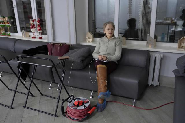 A local resident charges phone at the Point of Invincibility in Kyiv on January 9, 2026, where people can charge devices and warm themself, following Russian missile and drone attacks on Ukrainian energy infrastructure amid the Russian invasion of Ukraine. Mass heating outages caused by Russian strikes on Kyiv are set to last into the weekend, as the capital's mayor called on residents to temporarily leave the city with sub-zero temperatures expected to fall even lower. (Photo by Andrew Kravchenko / AFP)