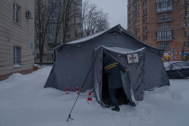 A Ukrainian rescue worker opens a tent of Point of Invincibility in Kyiv on January 9, 2026, where people can charge devices and warm themself, following Russian missile and drone attacks on Ukrainian energy infrastructure amid the Russian invasion of Ukraine. Mass heating outages caused by Russian strikes on Kyiv are set to last into the weekend, as the capital's mayor called on residents to temporarily leave the city with sub-zero temperatures expected to fall even lower. (Photo by Andrew Kravchenko / AFP)