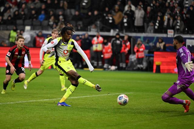 Dortmund's English midfielder #17 Carney Chukwuemeka (C) scores the 3-3 goal past Frankfurt's Brazilian goalkeeper #40 Kaua Santos (R) during the German first division Bundesliga football match between Eintracht Frankfurt and BVB Borussia Dortmund in Frankfurt am Main, western Germany, on January 9, 2026. (Photo by Kirill KUDRYAVTSEV / AFP) / DFL REGULATIONS PROHIBIT ANY USE OF PHOTOGRAPHS AS IMAGE SEQUENCES AND/OR QUASI-VIDEO