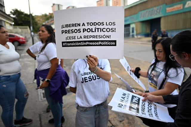 A demonstrator shows a sign that reads in Spanish "Release all political prisoners!, Stop the repression!" during a demonstration by relatives of political prisoners in demand of the release of their loved ones, near the notorious El Helicoide -a facility and prison owned by the Venezuelan government and used for both regular and political prisoners of the Bolivarian National Intelligence Service (SEBIN)- in Caracas on January 9, 2026. Venezuela began releasing a "large number" of political prisoners, including several foreigners, in a move praised by US President Donald Trump on January 9 as a step toward cooperation after the ouster of ruler Nicolas Maduro. (Photo by Juan BARRETO / AFP)
