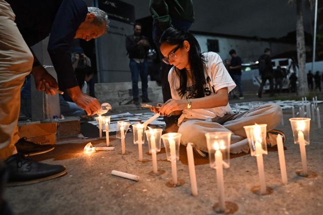 Relatives of political prisoners light candles in a vigil in demand of the release of their loved ones, near the notorious El Helicoide -a facility and prison owned by the Venezuelan government and used for both regular and political prisoners of the Bolivarian National Intelligence Service (SEBIN)- in Caracas on January 9, 2026. Venezuela began releasing a "large number" of political prisoners, including several foreigners, in a move praised by US President Donald Trump on January 9 as a step toward cooperation after the ouster of ruler Nicolas Maduro. (Photo by Juan BARRETO / AFP)