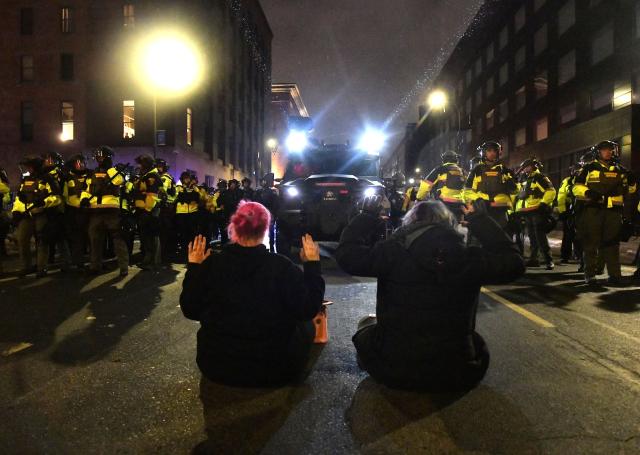 Two protesters sat on the road in front of Minnesota Conservation Officers as they were given the order to disperse after marching in protest against ICE for the fatal shooting of Renee Nicole Good in downtown Minneapolis, Minnesota on January 9, 2026. A US Immigration and Customs Enforcement (ICE) agent shot and killed 37-year-old Renee Nicole Good on the streets of Minneapolis on January 7, leading to huge protests and outrage from local leaders who rejected White House claims she was a domestic terrorist. (Photo by Octavio JONES / AFP)
