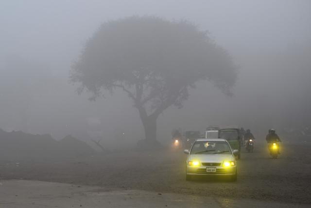 Commuters make their way amid dense fog on a cold winter morning in Lahore on January 10, 2026. (Photo by Arif ALI / AFP)