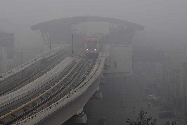 A metro train runs amid dense fog on a cold winter morning in Lahore on January 10, 2026. (Photo by Arif ALI / AFP)