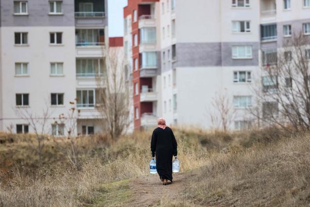 A woman walks with empty containers to fetch water during water scarcity in the Araplar neighbourhood of the Mamaklar district in Ankara on January 8, 2026. Because of this shortage, some neighborhoods in Ankara are experiencing water cuts for several hours a day, and many residents are forced to wait in line at public fountains to fill their containers. (Photo by Adem ALTAN / AFP)