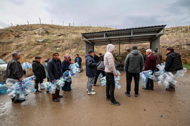 People wait to obtain water during water shotage in the Araplar neighborhood of the Mamaklar district in Ankara on January 8, 2026. Because of this shortage, some neighborhoods in Ankara are experiencing water cuts for several hours a day, and many residents are forced to wait in line at public fountains to fill their containers. (Photo by Adem ALTAN / AFP)