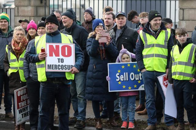 People hold placards as they gather to support Irish farmers taking part in a protest against the EU-Mercosur trade deal, in the town of Athlone on January 10, 2026. Several thousand Irish farmers protested on January 10 against the European Union's trade deal with the South American bloc Mercosur, a day after EU states approved the treaty despite opposition from Ireland and France. (Photo by Gareth CHANEY / AFP)