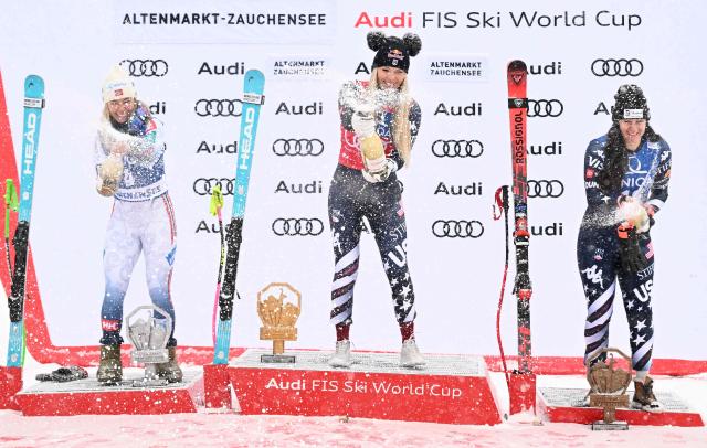(L-R) Second placed Norway's Kajsa Vickhoff Lie, winner US' Lindsey Vonn and third placed US' Jacqueline Wiles celebrate on the podium with sparkling wine after the Women's Downhill event of the FIS Alpine Ski World Cup in Altenmarkt Zauchensee, Austria, on January 10, 2026. (Photo by BARBARA GINDL / APA / AFP) / Austria OUT
