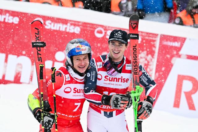 First-placed Switzerland's Marco Odermatt and third-placed France's Leo Anguenot celebrate after the second run of the Men's Giant Slalom, part of the FIS Alpine Ski World Cup 2025-2026 in Adelboden, soutwestern Switzerland on January 10, 2026. (Photo by Fabrice COFFRINI / AFP)