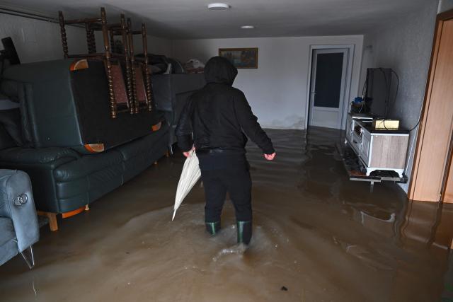 A man inspects his flooded house near the town of Lipjan on January 10, 2026, after torrential rains across Kosovo. (Photo by Armend NIMANI / AFP)