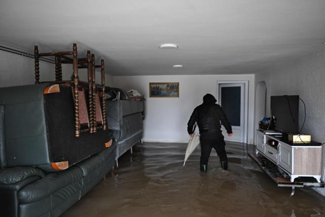 A man inspects his flooded house near the town of Lipjan on January 10, 2026, after torrential rains across Kosovo. (Photo by Armend NIMANI / AFP)