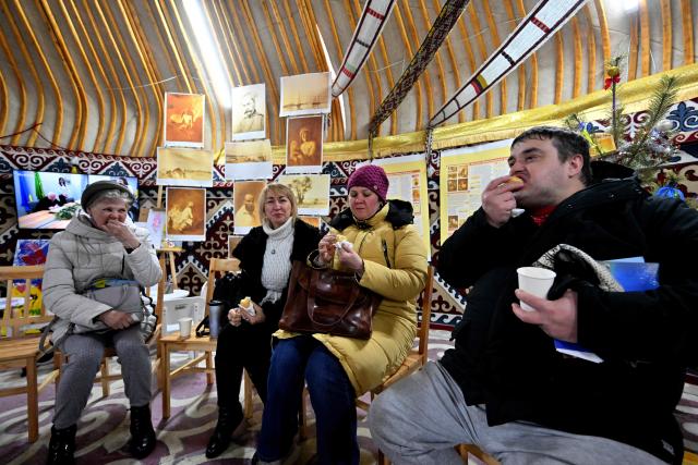 Members of the public drink free tea with traditional Kazakh bread baursaki, as they take the opportunity to get warm and charge their digital objects as part of the initiative "Yurt of Invincibility", organised by representatives of the Kazakh diaspora in a park in the center of Kyiv on January 10, 2026, amid Russian invasion in Ukraine. The Yurt of Invincibility is placed in a traditional Kazakh yurt and organized in a similar way with the Points of Invincibility, heating points organised by the government and volunteers around the country, as repeated Russian attacks have left Ukraine's energy grid teetering on the brink of collapse and have disrupted power and water supplies to millions over recent weeks. (Photo by Sergei SUPINSKY / AFP)
