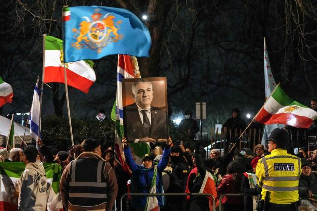 Anti-Iranian regime protesters hold up a portrait of Iranian opposition leader and son of the last shah of Iran Mohammad Reza Pahlavi, Reza Pahlavi (C), as they take part in a demonstration outside the Iranian Embassy in central London on January 10, 2026. (Photo by CARLOS JASSO / AFP)
