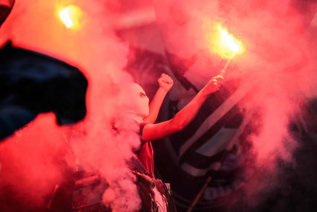 An Angers supporter holds flares in the stands during the French Cup round of 32 football match between Angers SCO and Toulouse FC at the Raymond-Kopa Stadium in Angers, western France on January 10, 2026. (Photo by Loic VENANCE / AFP)