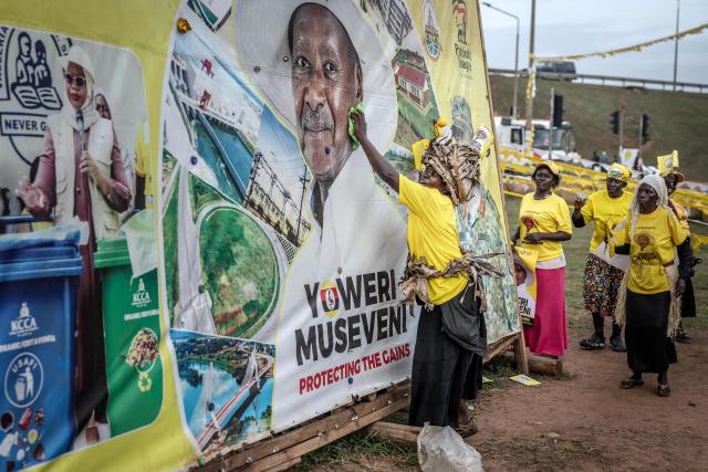 Efrance Nsudde (C), 50, a supporter for Uganda’s incumbent president and National Resistance Movement (NRM) presidential candidate Yoweri Museveni, wipes an electoral billboard with other supporters at a busy roundabout, ahead of the 2026 Ugandan general elections, in Kampala on January 10, 2026. (Photo by Luis TATO / AFP)