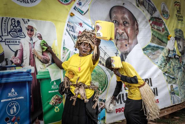 Efrance Nsudde (L), 50, a supporter for Uganda’s incumbent president and National Resistance Movement (NRM) presidential candidate Yoweri Museveni, wipes an electoral billboard with other supporters at a busy roundabout, ahead of the 2026 Ugandan general elections, in Kampala on January 10, 2026. (Photo by Luis TATO / AFP)