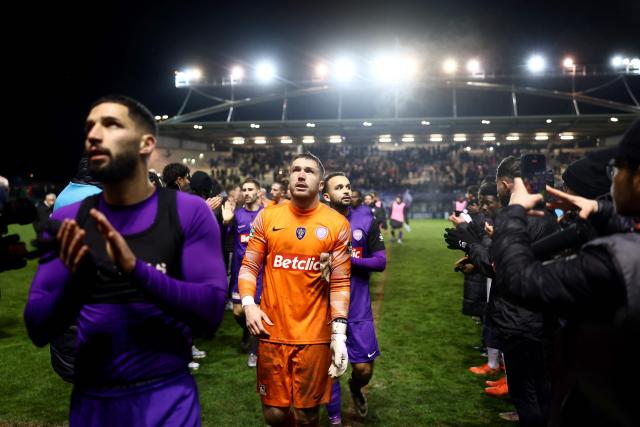 Hauts Lyonnais players leave the pitch as winning team Lorient's players line up in respect at the end of the French Cup round of 32 football match between Hauts Lyonnais and FC Lorient at the Envol Stadium in Andrezieux-Bouthéon, central-eastern France, on January 10, 2026. (Photo by Alex MARTIN / AFP)