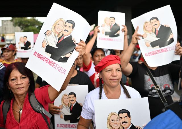 Demonstrators hold signs reading "We want them back" with the image of deposed Venezuelan president Nicolas Maduro and his wife Cilia Flores, snatched and taken to New York on January 3 to face trial on drug and weapons charges, during a march in Caracas on January 10, 2026. Venezuela was set to hold talks with US envoys in Caracas on restoring diplomatic ties, days after US forces deposed Nicolas Maduro as its president and US President Donald Trump's claimed to be "in charge" of the South American country. (Photo by Juan BARRETO / AFP)