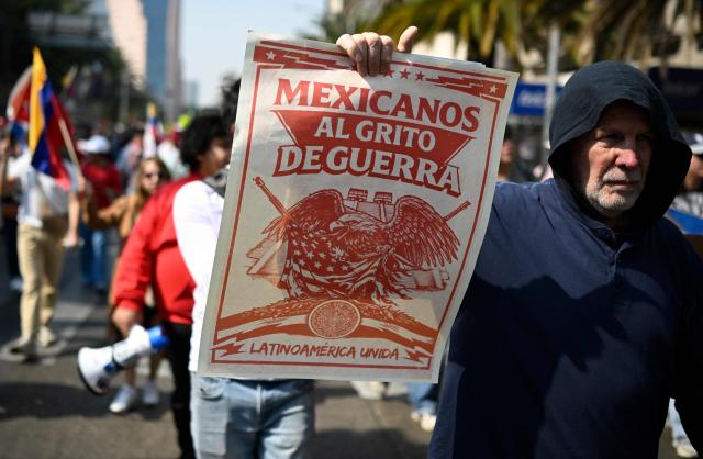 A demonstrator holds a sign during a march in Mexico City on January 10, 2026, in support of deposed Venezuelan president Nicolas Maduro and his wife Cilia Flores and against a possible US intervention in Mexico. Mexican President Claudia Sheinbaum said her government wanted closer security coordination with the US and repeatedly opposed any foreign military intervention after Donald Trump threatened to launch ground attacks against drug cartels. (Photo by Alfredo ESTRELLA / AFP)