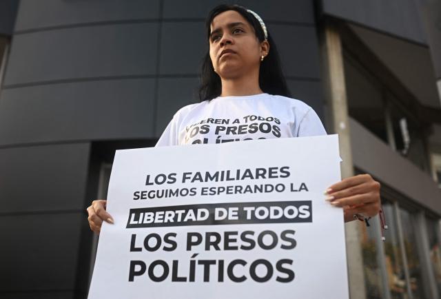 Fabiana Vera, sister of political prisoner Jackson Vera, holds a sign demanding freedom for all political prisoners at El Helicoide -a facility and prison owned by the Venezuelan government and used for both regular and political prisoners of the Bolivarian National Intelligence Service (SEBIN)- in Caracas on January 10, 2026. Venezuelan authorities are releasing a "large number" of prisoners, some of them foreigners, five days after US forces ousted president Nicolas Maduro. (Photo by Federico PARRA / AFP)