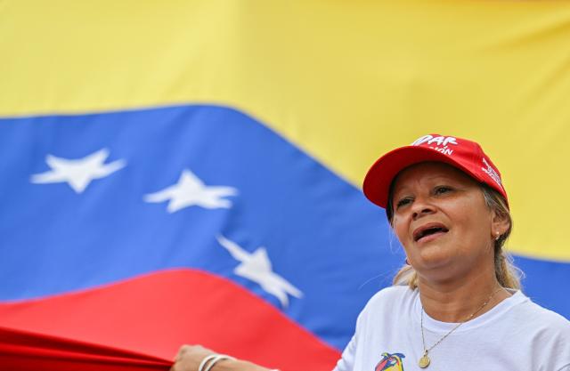 A demonstrator shouts slogans in front of a Venezuelan flag during a rally in support of ousted Venezuela's President Nicolas Maduro in Caracas on January 10, 2026. The US State Department on January 10, urged Americans in Venezuela to leave the country "immediately," citing risks from armed militias searching vehicles for US citizens at roadblocks. (Photo by Juan BARRETO / AFP)