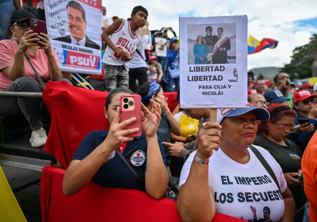 A demonstrator holds a picture of ousted Venezuela's President Nicolas Maduro and his wife Cilia Flores during a rally in their support in Caracas on January 10, 2026. The US State Department on January 10, urged Americans in Venezuela to leave the country "immediately," citing risks from armed militias searching vehicles for US citizens at roadblocks. (Photo by Juan BARRETO / AFP)