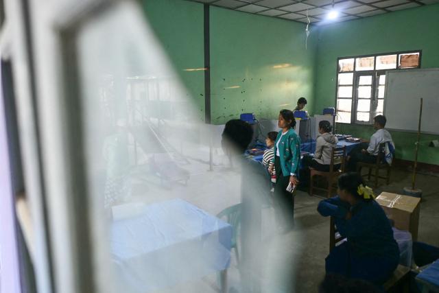 People cast their vote inside a polling station during the second phase of Myanmar's general election at Kawhmu township in Yangon on January 11, 2026. Myanmar's junta opened polls on January 11 in the second phase of elections, continuing a vote democracy watchdogs say is letting the military prolong its rule in a civilian guise. (Photo by Sai Aung MAIN / AFP)