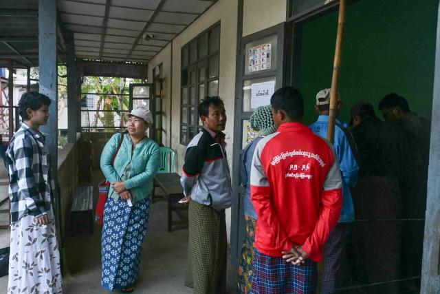 People wait to vote at a polling station during the second phase of Myanmar's general election at Kawhmu township in Yangon on January 11, 2026. Myanmar's junta opened polls on January 11 in the second phase of elections, continuing a vote democracy watchdogs say is letting the military prolong its rule in a civilian guise. (Photo by Sai Aung MAIN / AFP)