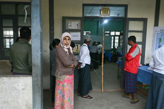 People wait to vote at a polling station during the second phase of Myanmar's general election at Kawhmu township in Yangon on January 11, 2026. Myanmar's junta opened polls on January 11 in the second phase of elections, continuing a vote democracy watchdogs say is letting the military prolong its rule in a civilian guise. (Photo by Sai Aung MAIN / AFP)