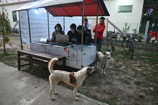 Election volunteers check voter lists at a booth outside a polling station during the second phase of Myanmar's general election at Kawhmu township in Yangon on January 11, 2026. Myanmar's junta opened polls on January 11 in the second phase of elections, continuing a vote democracy watchdogs say is letting the military prolong its rule in a civilian guise. (Photo by Sai Aung MAIN / AFP)