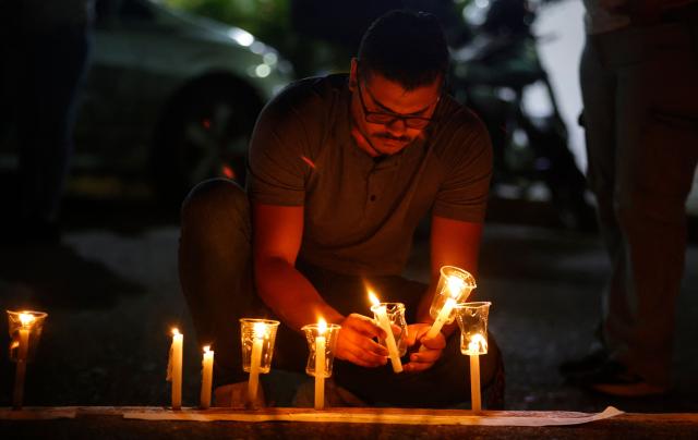 A man lit candles during a vigil to demand the release of political prisoners outside El Rodeo I prison in Guatire, Miranda State, some 30 kilometers east of Caracas on January 10, 2026. Venezuela on January 8 began releasing a "large number" of political prisoners, including several foreigners, in a move praised by US President Donald Trump as a step toward cooperation after the ouster of ruler Nicolas Maduro. (Photo by Pedro MATTEY / AFP)