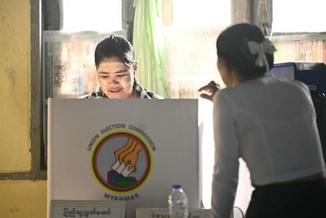 A woman casts her vote at a polling station during the second phase of Myanmar's general election at Kawhmu township in Yangon on January 11, 2026. Myanmar's junta opened polls on January 11 in the second phase of elections, continuing a vote democracy watchdogs say is letting the military prolong its rule in a civilian guise. (Photo by Sai Aung MAIN / AFP)