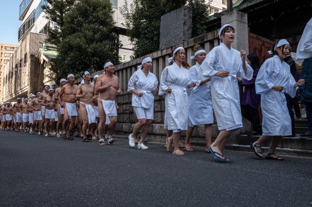 Participants run to warm up before taking a bath in cold water to purify their souls and bodies during a New Year ritual at the Teppozu Inari Shrine in Tokyo on January 11, 2026. (Photo by Philip FONG / AFP)