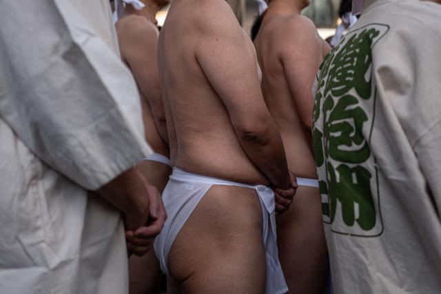 Participants prepare to take a bath in cold water to purify their souls and bodies during a New Year ritual at the Teppozu Inari Shrine in Tokyo on January 11, 2026. (Photo by Philip FONG / AFP)