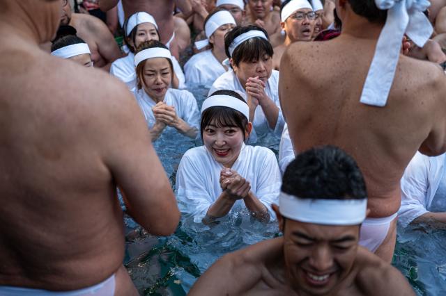 Participants take a bath in cold water to purify their souls and bodies during a New Year ritual at the Teppozu Inari Shrine in Tokyo on January 11, 2026. (Photo by Philip FONG / AFP)