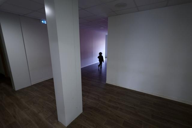 A child plays in a corridor at an empty school near the Blandan's park in Lyon, south-eastern France, on January 10, 2026 where homeless families are being housed by a collective. Classrooms turned into dormitories and a cafeteria: more than 80 children without a roof over their heads are occupying an empty school in Lyon with their parents, in an operation of a "highly exceptional" scale carried out on January 9, 2026 evening by the collective "Jamais Sans Toit" (JST) due to the lack of housing solutions. (Photo by Alex MARTIN / AFP)