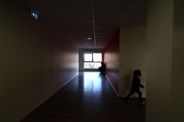 A child plays in a corridor at an empty school near the Blandan's park in Lyon, south-eastern France, on January 10, 2026 where homeless families are being housed by a collective. Classrooms turned into dormitories and a cafeteria: more than 80 children without a roof over their heads are occupying an empty school in Lyon with their parents, in an operation of a "highly exceptional" scale carried out on January 9, 2026 evening by the collective "Jamais Sans Toit" (JST) due to the lack of housing solutions. (Photo by Alex MARTIN / AFP)