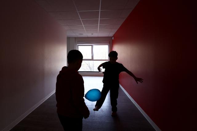 Two boys play in a corridor at an empty school near the Blandan's park in Lyon, south-eastern France, on January 10, 2026 where homeless families are being housed by a collective. Classrooms turned into dormitories and a cafeteria: more than 80 children without a roof over their heads are occupying an empty school in Lyon with their parents, in an operation of a "highly exceptional" scale carried out on January 9, 2026 evening by the collective "Jamais Sans Toit" (JST) due to the lack of housing solutions. (Photo by Alex MARTIN / AFP)