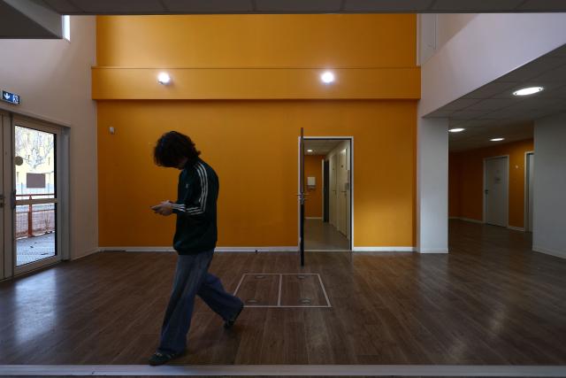 A young man walks at an empty school near the Blandan's park in Lyon, south-eastern France, on January 10, 2026 where homeless families are being housed by a collective. Classrooms turned into dormitories and a cafeteria: more than 80 children without a roof over their heads are occupying an empty school in Lyon with their parents, in an operation of a "highly exceptional" scale carried out on January 9, 2026 evening by the collective "Jamais Sans Toit" (JST) due to the lack of housing solutions. (Photo by Alex MARTIN / AFP)